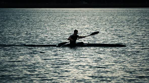 Sillouette of man kayaking on lake alt
