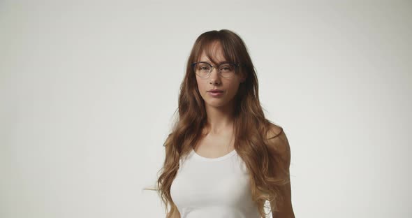 Beautiful Young Woman In White Putting On Glasses