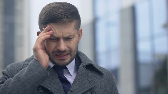 Businessman Touching Temple Feeling Sudden Headache, Taking Pill for Pain Relief