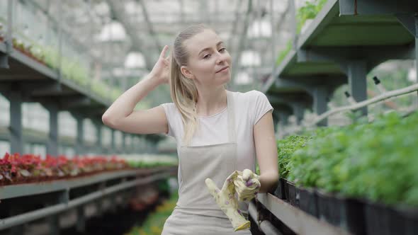 Smiling Pretty Girl Taking Off Gloves and Looking at Camera. Portrait of Positive Young Caucasian alt