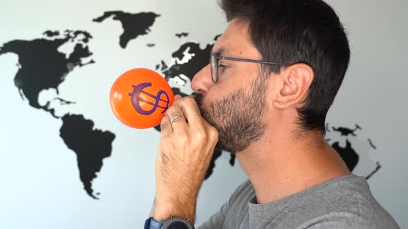 Man Blowing Up a Balloon with Dollar Symbol and a World Map on the Background