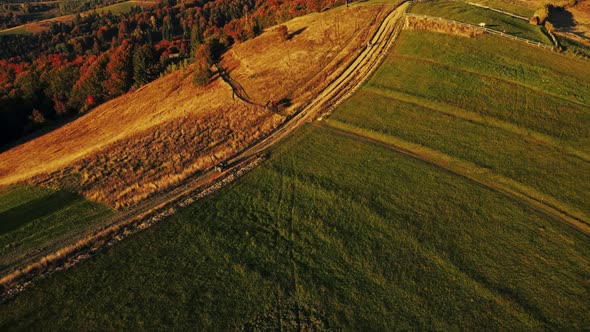 Tourist riding on all-terrain quadricycle vehicle along mountain range in sunset lights. alt