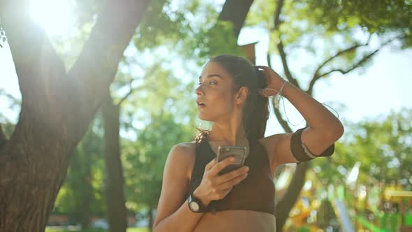 Young Beautiful Sportive Girl Resting Listening Music in Park alt