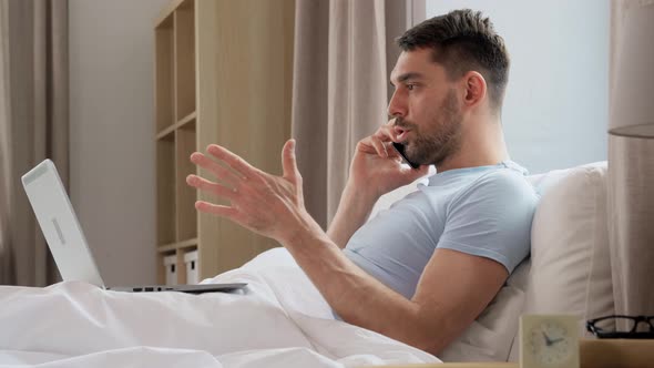 Man with Folder Calling on Phone in Bed at Home alt
