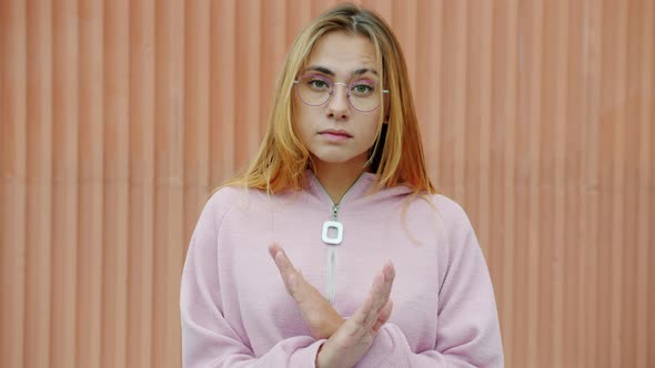 Portrait of Displeased Lady Waving Head and Crossing Hands Saying No Outdoors on Wall Background alt