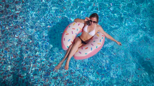 A Beautiful Young Woman Swims in the Pool on an Inflatable Circle. Rest at the Resort. alt
