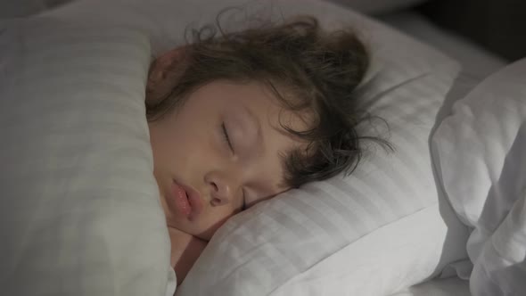 Beautiful kid sleeps in bed. alt