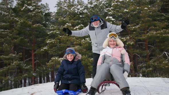 Winter Holidays Happy Grandparents Together with Their Grandson Have Fun Sledding From a Snowy Hill