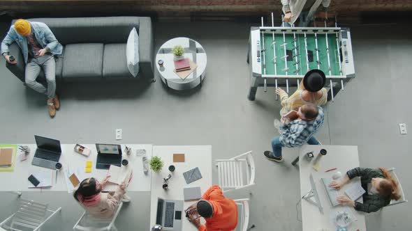 Creative Youth Working at Desks and Playing Table Football Indoors in Modern Coworking Place alt