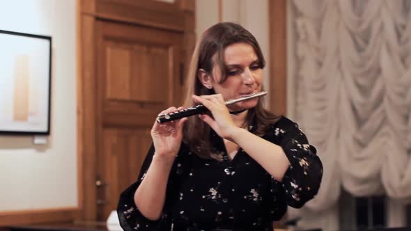 Young woman playing a piccolo flute, closeup portrait of a musician alt