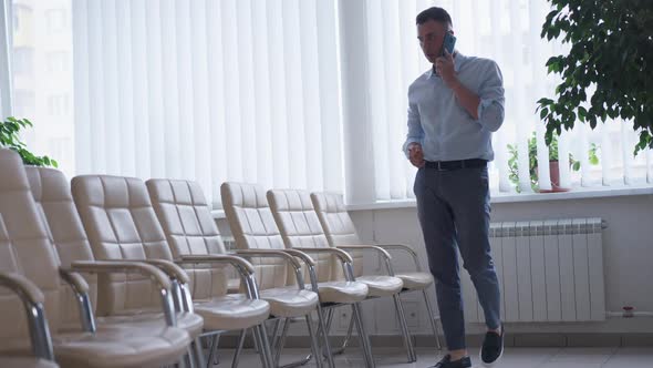 Wide Shot Busy Young Man Talking on Phone Walking in Modern Comfortable Office alt