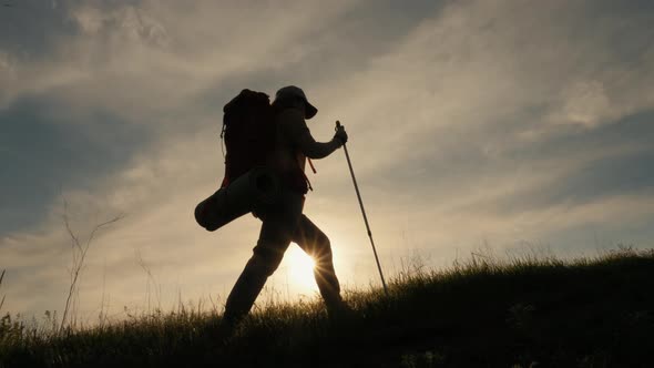 Silhouette of Walking Woman with Backpack on the Mountain alt