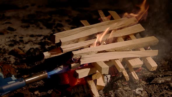 Close Up Slow Motion Shot of Wood Fire Starting to Rise a Man Kindles a Fire with a Gas Burner