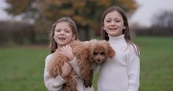 Portrait shot of two little girls smiling and playing together with a dog
