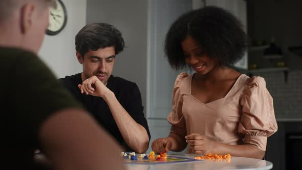 Cheerful AfricanAmerican Young Woman Throwing Dice and Moving Figures Playing in Board Game with alt