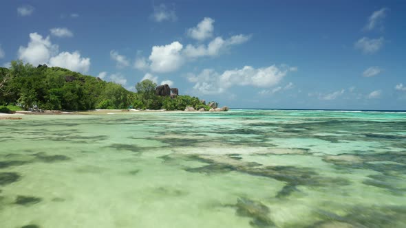 Aerial dolly close to surface of shallow water Anse Source d'Argent alt