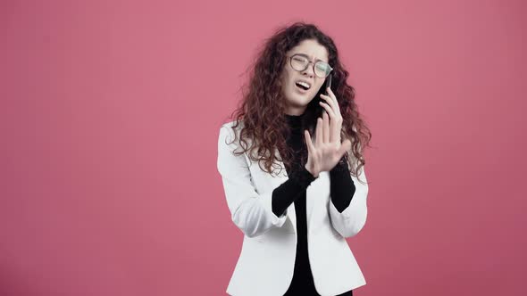 Agitated Young Woman with Curly Hair Talking on the Phone with Contempt Gesturing with Her Hand alt