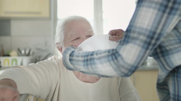 Daughter Puts On Old Mother's Medical Mask To Protect During Epidemic Of Adult Infection. alt