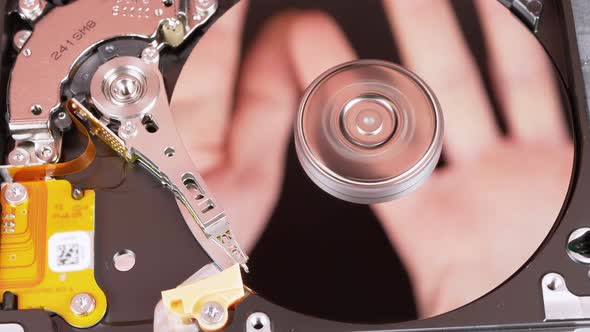 Hard Disk Drive Inside. Reflection of Palms on Mirror Surface of a Magnetic Disk alt