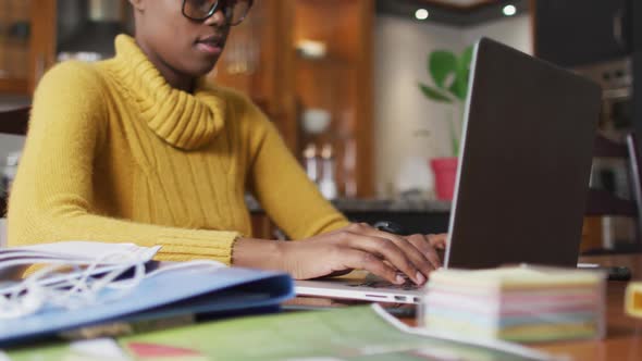 African american woman using laptop while working from home alt