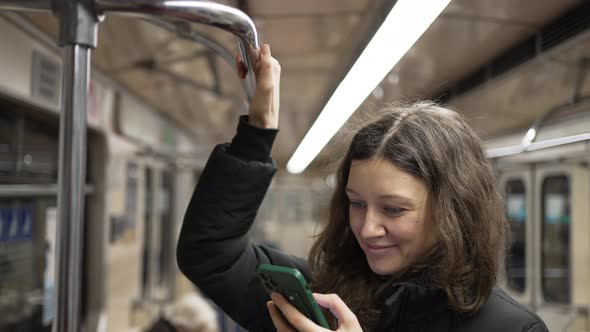 A Nice Woman with a Phone in Her Hands Goes to the Subway and Takes Hold of the Handrail alt