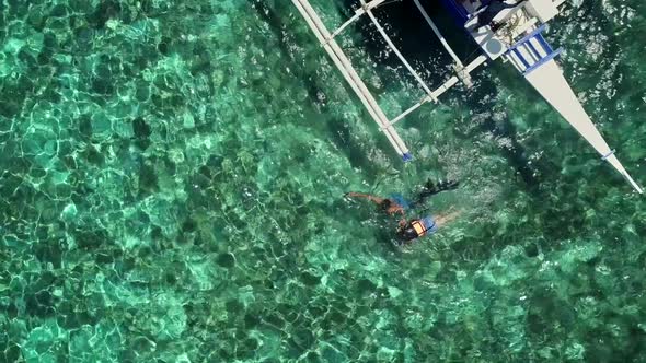 Aerial view of two people snorkeling in turquoise water in Panagsama Beach. alt