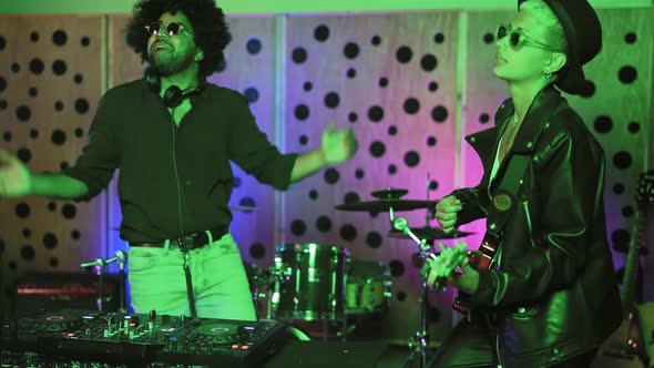 Young happy people playing music with dj mixer and guitar in house studio alt