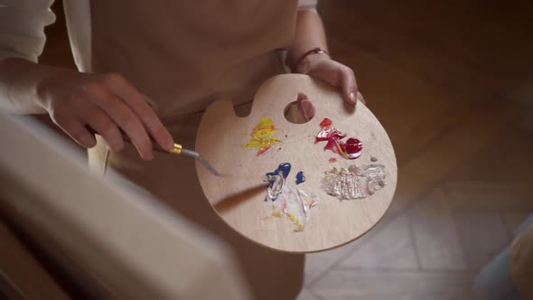 Young Artist Using a Palette Knife Mix Colors on Palette