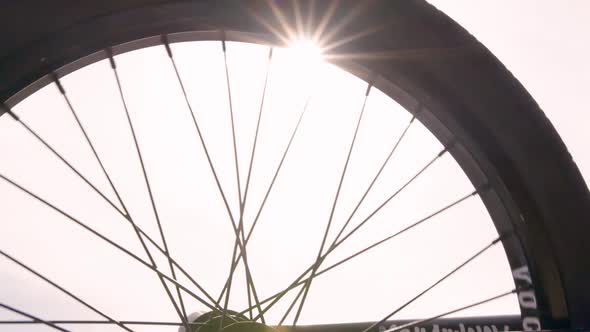 The wheel of the bike is spinning, against the backdrop of the bright sun