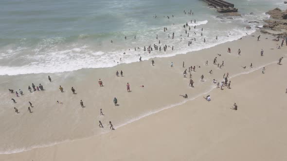 Drone Flying Over Coastline with People Seen Swimming