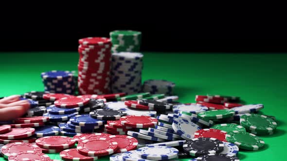 Hand Counts Poker Chips Lying on a Green Table on a Black Background in Close-up alt
