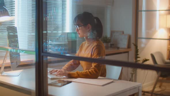 Asian Female Stock Market Trader Working in Office at Night alt