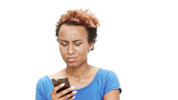 Upset Young Beautiful African Girl Looking at Phone Over White Background alt