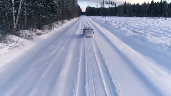Aerial view of a car driving in the snowy forest in Estonia alt