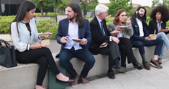 Multiethnic business people doing lunch break outdoor from office building alt