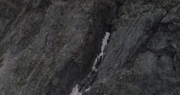 Aerial close up of snow patched cliffs. alt