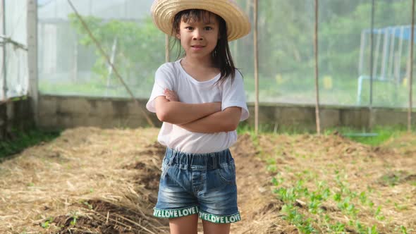 Little girl wearing a hat helps her mother in the garden. alt