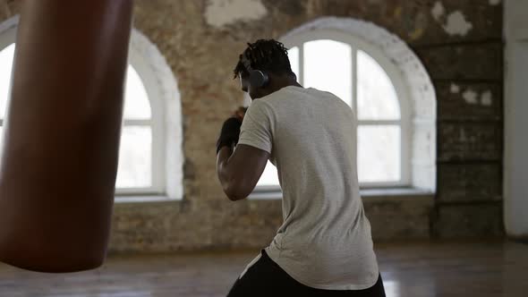 Afro American Boxer Punching the Heavy Bag in the Gym alt