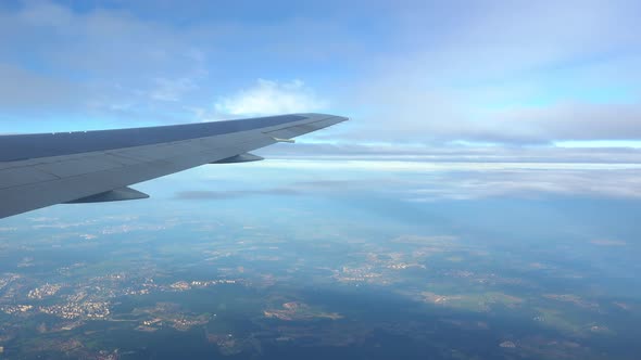 A View of Land from Side of Plane from Window. Wing of Plane in Porthole