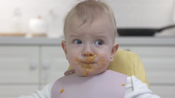 Feeding Baby in the Kitchen at Home Messy Face of Oneyearold Toddler Closeup