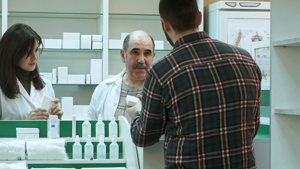 Attractive woman and senior pharmacist listening to male