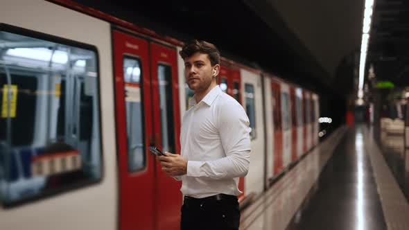 Businessman with Smartphone Waiting for Train alt