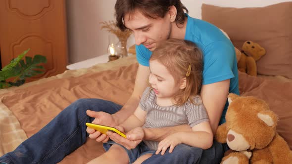 Father and Daughter Watch Cartoon on Phone Home Interior Training