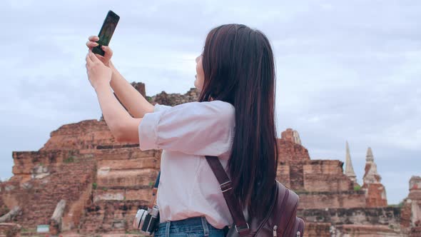 Asian backpacker blogger woman casual take selfie video call on mobile phone sharing live online.