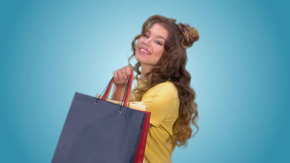 Attractive Young Girl with Shopping Bags Spinning Around Herself and Posing Looking at the Camera alt