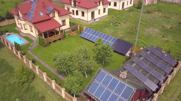 Aerial view of a residential private house with solar panels on roof and wind generator turbine. alt