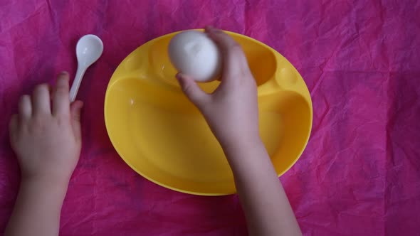 Top view of child's hands peel boiled egg on table with copy space