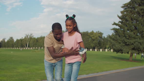 Dad Helping Teenage Girl To Ride Roller Skates alt