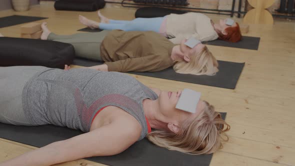 Women Meditating on Floor with Eye Pillows alt