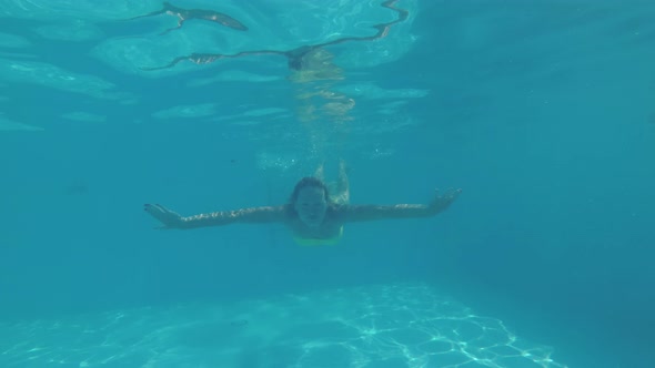 A Young Active Woman in a Bikini Swims Underwater in an Outdoor Swimming Pool alt